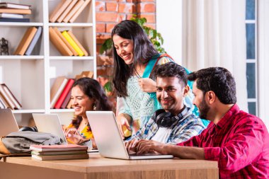 Hintli dört üniversite öğrencisi ya da üniversite öğrencileri masada çalışmak için dizüstü bilgisayar kullanıyor