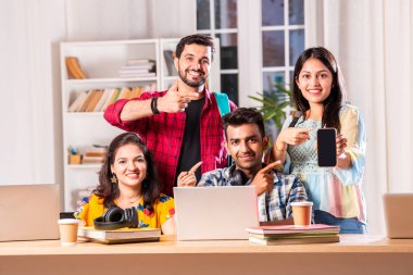 Hintli dört üniversite öğrencisi ya da üniversite öğrencileri masada çalışmak için dizüstü bilgisayar kullanıyor