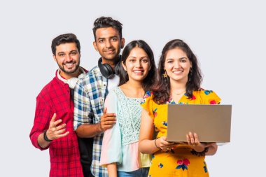 Hintli Asyalı üniversite öğrencileri dizüstü bilgisayarlarını kullanarak boş yerleri gösteriyorlar veya başarıyı kutluyorlar.