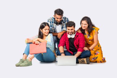 Hintli Asyalı üniversite öğrencileri dizüstü bilgisayarlarını kullanarak boş yerleri gösteriyorlar veya başarıyı kutluyorlar.