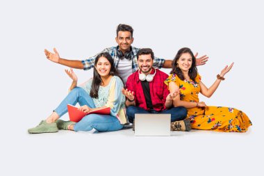 Hintli Asyalı üniversite öğrencileri dizüstü bilgisayarlarını kullanarak boş yerleri gösteriyorlar veya başarıyı kutluyorlar.