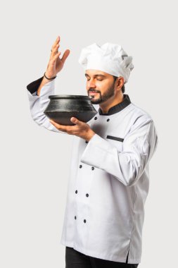 Beyaz elbiseli Hintli bir şef elinde biryani terracotta çömleği tutuyor.