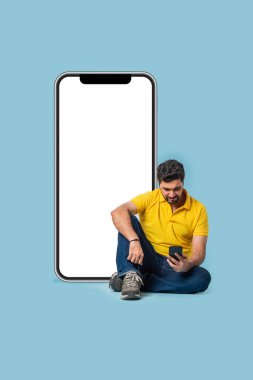 Geniş, boş ekranlı, açık mavi arka planlı Asyalı genç adam.