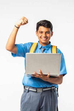 Hintli Asyalı üniformalı çocuk dizüstü bilgisayar kullanıyor, beyaz arka planda tek başına duruyor.