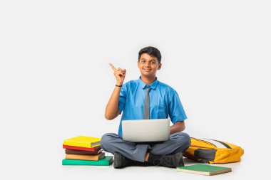 Kitap ve dizüstü bilgisayarlı Hintli öğrenci boş bir yeri işaret ediyor, eğitimi destekliyor.