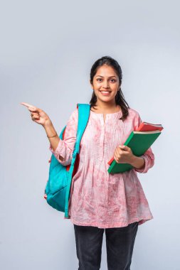 Sırt çantası, dizüstü bilgisayarı, işaret eden kitapları olan Asyalı genç kız.