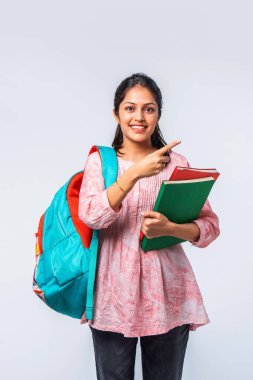 Sırt çantası, dizüstü bilgisayarı, işaret eden kitapları olan Asyalı genç kız.
