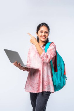 Sırt çantası, dizüstü bilgisayarı, işaret eden kitapları olan Asyalı genç kız.