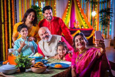 Mutlu Hintli Asyalı aile, Hindu festivalini kutluyor, yemek yiyor, evi süslüyor.