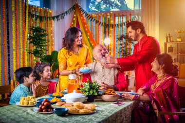 Mutlu Hintli Asyalı aile, Hindu festivalini kutluyor, yemek yiyor, evi süslüyor.