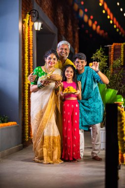 Çocuklu mutlu Hintli aile balkonda Diwali 'yi kutluyor, ellerinde Pooja thali, besan laddu