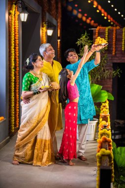 Çocuklu mutlu Hintli aile balkonda Diwali 'yi kutluyor, ellerinde Pooja thali, besan laddu