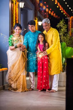 Indian family of four celebrating Diwali with sparklers, creating festive memories together clipart