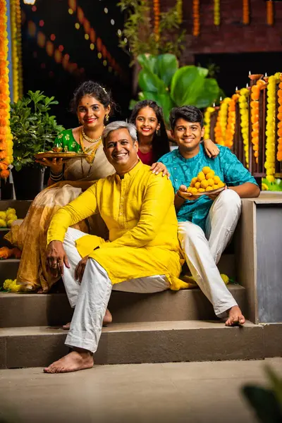 stock image Indian family of four celebrating Diwali on stairs, holding festive items, smiling at the camera