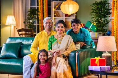 Dört kişilik Hint ailesi Diwali festivalinde hediye kutularıyla kanepede oturuyor.