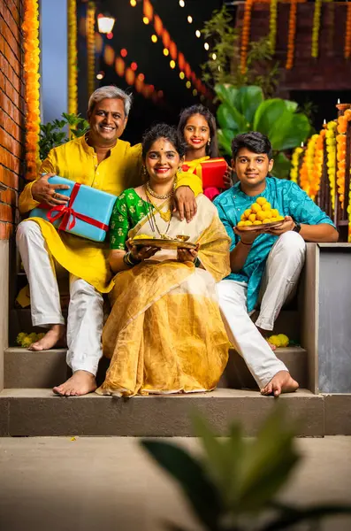 stock image Indian family of four celebrating Diwali on stairs, holding festive items, smiling at the camera