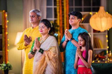 Indian family of four celebrating Diwali with sparklers, creating festive memories together clipart