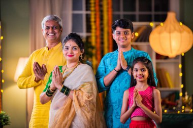 Indian family of four celebrating Diwali with sparklers, creating festive memories together clipart