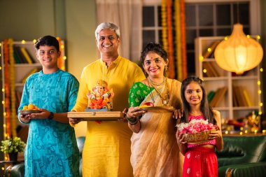 Geleneksel Maharashtrian kıyafetli genç Hint ailesi Chaturthi kutlamasında Ganesh idolünü karşılıyor.