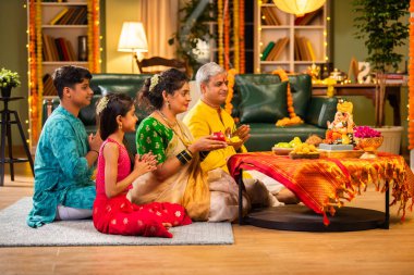 Etnik olarak Hint ailesi festivalde laddu ve puja thali ile Ganesh Chaturthi puja performansı sergiliyor.