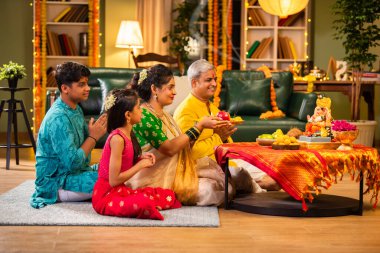 Etnik olarak Hint ailesi festivalde laddu ve puja thali ile Ganesh Chaturthi puja performansı sergiliyor.