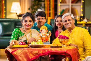 Etnik olarak Hint ailesi festivalde laddu ve puja thali ile Ganesh Chaturthi puja performansı sergiliyor.