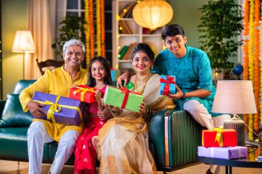 Dört kişilik Hint ailesi Diwali festivalinde hediye kutularıyla kanepede oturuyor.