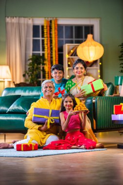 Dört kişilik Hint ailesi Diwali festivalinde hediye kutularıyla kanepede oturuyor.