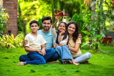 Çocukları parkta oturmuş birbirlerini kucaklayan mutlu Hintli çift ve kızlarının kucağına aldığı oyuncak uçağa hayranlık duyuyorlar. Aşkı, aile zamanını, hayal gücünü ve beraberliği sembolize ediyorlar.