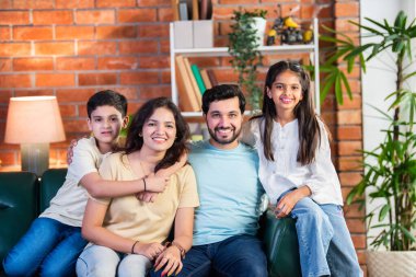 Dört kişilik neşeli Hintli aile evde kaliteli zaman geçiriyorlar. Aileler ve çocuklar kanepede oturuyor, birlikte gülüyor ve oynuyorlar. Mutlu aile bağları ve aşk anları yakalıyorlar.