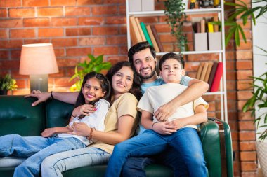 Dört kişilik neşeli Hintli aile evde kaliteli zaman geçiriyorlar. Aileler ve çocuklar kanepede oturuyor, birlikte gülüyor ve oynuyorlar. Mutlu aile bağları ve aşk anları yakalıyorlar.