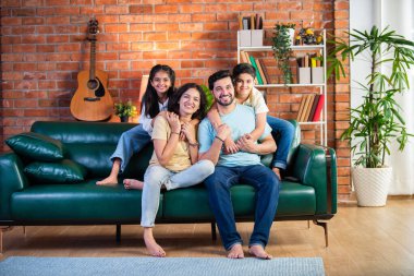 Dört kişilik neşeli Hintli aile evde kaliteli zaman geçiriyorlar. Aileler ve çocuklar kanepede oturuyor, birlikte gülüyor ve oynuyorlar. Mutlu aile bağları ve aşk anları yakalıyorlar.