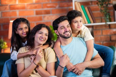 Dört kişilik neşeli Hintli aile evde kaliteli zaman geçiriyorlar. Aileler ve çocuklar kanepede oturuyor, birlikte gülüyor ve oynuyorlar. Mutlu aile bağları ve aşk anları yakalıyorlar.