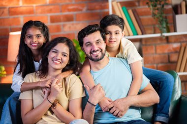 Dört kişilik neşeli Hintli aile evde kaliteli zaman geçiriyorlar. Aileler ve çocuklar kanepede oturuyor, birlikte gülüyor ve oynuyorlar. Mutlu aile bağları ve aşk anları yakalıyorlar.