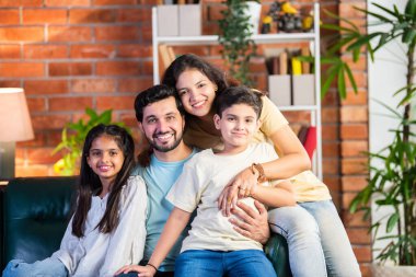 Dört kişilik neşeli Hintli aile evde kaliteli zaman geçiriyorlar. Aileler ve çocuklar kanepede oturuyor, birlikte gülüyor ve oynuyorlar. Mutlu aile bağları ve aşk anları yakalıyorlar.