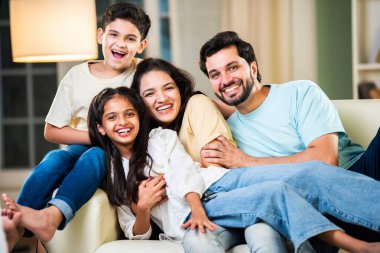 Dört kişilik neşeli Hintli aile evde kaliteli zaman geçiriyorlar. Aileler ve çocuklar kanepede oturuyor, birlikte gülüyor ve oynuyorlar. Mutlu aile bağları ve aşk anları yakalıyorlar.