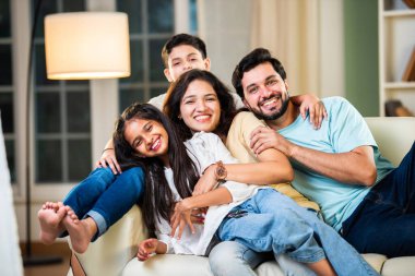 Dört kişilik neşeli Hintli aile evde kaliteli zaman geçiriyorlar. Aileler ve çocuklar kanepede oturuyor, birlikte gülüyor ve oynuyorlar. Mutlu aile bağları ve aşk anları yakalıyorlar.