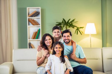 Dört kişilik neşeli Hintli aile evde kaliteli zaman geçiriyorlar. Aileler ve çocuklar kanepede oturuyor, birlikte gülüyor ve oynuyorlar. Mutlu aile bağları ve aşk anları yakalıyorlar.