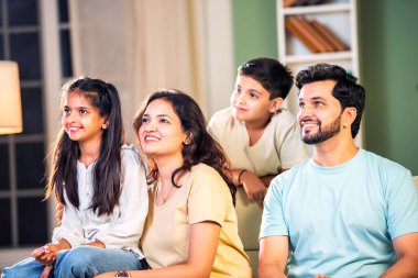 Dört kişilik neşeli Hintli aile evde kaliteli zaman geçiriyorlar. Aileler ve çocuklar kanepede oturuyor, birlikte gülüyor ve oynuyorlar. Mutlu aile bağları ve aşk anları yakalıyorlar.
