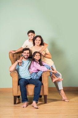 Dört kişilik neşeli Hintli aile evde kaliteli zaman geçiriyorlar. Aileler ve çocuklar kanepede oturuyor, birlikte gülüyor ve oynuyorlar. Mutlu aile bağları ve aşk anları yakalıyorlar.