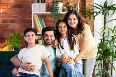 Dört kişilik neşeli Hintli aile evde kaliteli zaman geçiriyorlar. Aileler ve çocuklar kanepede oturuyor, birlikte gülüyor ve oynuyorlar. Mutlu aile bağları ve aşk anları yakalıyorlar.