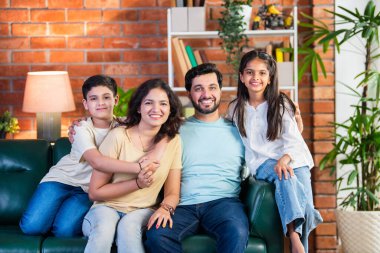 Dört kişilik neşeli Hintli aile evde kaliteli zaman geçiriyorlar. Aileler ve çocuklar kanepede oturuyor, birlikte gülüyor ve oynuyorlar. Mutlu aile bağları ve aşk anları yakalıyorlar.
