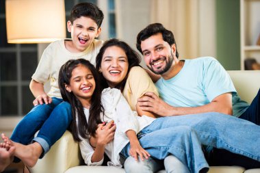 Dört kişilik neşeli Hintli aile evde kaliteli zaman geçiriyorlar. Aileler ve çocuklar kanepede oturuyor, birlikte gülüyor ve oynuyorlar. Mutlu aile bağları ve aşk anları yakalıyorlar.