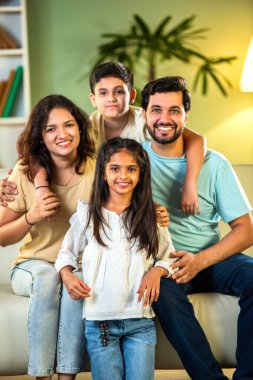 Dört kişilik neşeli Hintli aile evde kaliteli zaman geçiriyorlar. Aileler ve çocuklar kanepede oturuyor, birlikte gülüyor ve oynuyorlar. Mutlu aile bağları ve aşk anları yakalıyorlar.