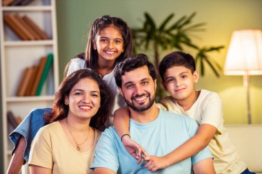 Dört kişilik neşeli Hintli aile evde kaliteli zaman geçiriyorlar. Aileler ve çocuklar kanepede oturuyor, birlikte gülüyor ve oynuyorlar. Mutlu aile bağları ve aşk anları yakalıyorlar.