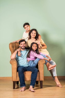 Dört kişilik neşeli Hintli aile evde kaliteli zaman geçiriyorlar. Aileler ve çocuklar kanepede oturuyor, birlikte gülüyor ve oynuyorlar. Mutlu aile bağları ve aşk anları yakalıyorlar.