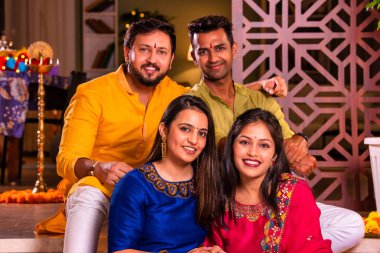 Mutlu Hintli çiftler ve geleneksel arkadaşlar Diwali 'yi evde içeceklerle, tatlılarla, hediyelerle, çiçeklerle, selfie çekerek ve birlikte eğlenerek kutlarlar..