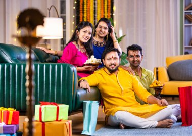 Mutlu Hintli çiftler ve geleneksel arkadaşlar Diwali 'yi evde içeceklerle, tatlılarla, hediyelerle, çiçeklerle, selfie çekerek ve birlikte eğlenerek kutlarlar..