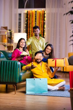 Mutlu Hintli çiftler ve geleneksel arkadaşlar Diwali 'yi evde içeceklerle, tatlılarla, hediyelerle, çiçeklerle, selfie çekerek ve birlikte eğlenerek kutlarlar..