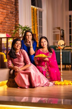 Geleneksel Hintli neşeli Asyalı genç kız ya da kız kardeşler geleneksel Samai veya diya etrafında canlı çiçek Rangoli yaratarak Diwali 'nin lüks evlerinde kutlamalarını yapıyorlar.